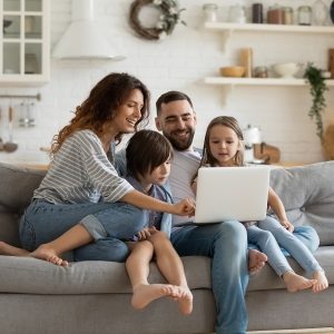 Parents with 2 kids looking happily at laptop implying they are doing online counseling.