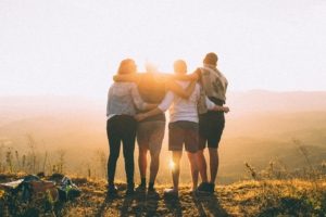 family of 4 adults looking at sunset with arms around each other, suggesting they did family counseling