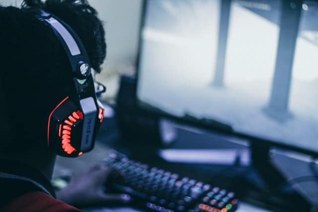 Person wearing gaming headphones at a computer, representing the intersection of gaming culture and mental health therapy at Bedrock Psychology Group in Northbrook, IL